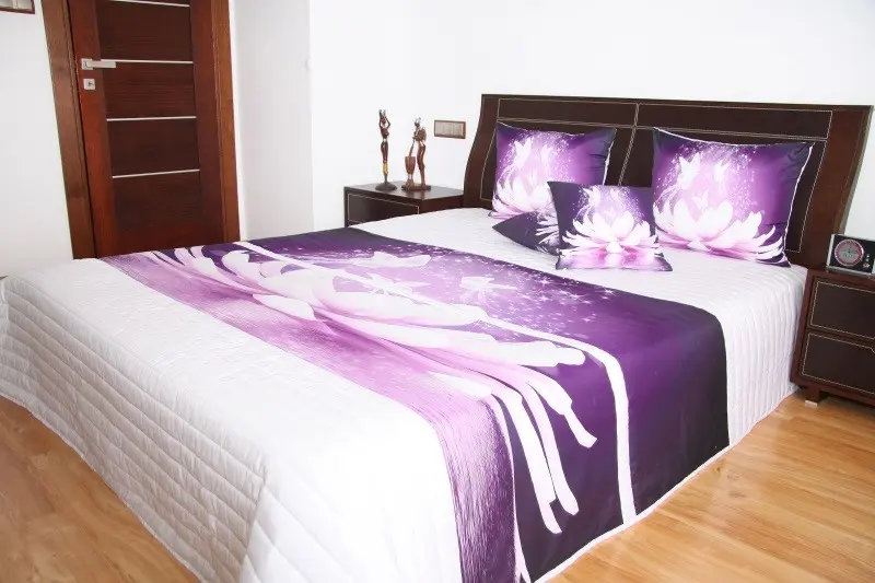 Přehoz na postel bílé barvy s motivem fialového květu Šířka: 220 cm | Délka: 240 cm